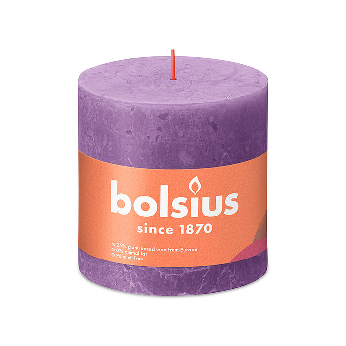 Eine durchgefärbte Rustik Stumpenkerze in der Farbe Blühendes Veilchen mit den Maßen 100/100mm (H/DM). Der Banderole kann man die Marke "Bolsius" sowie die Hinweise "25% pflanzenbasiertes EU-Wachs", "0% tierisches Fett" und "Ohne Palmöl" ablesen.