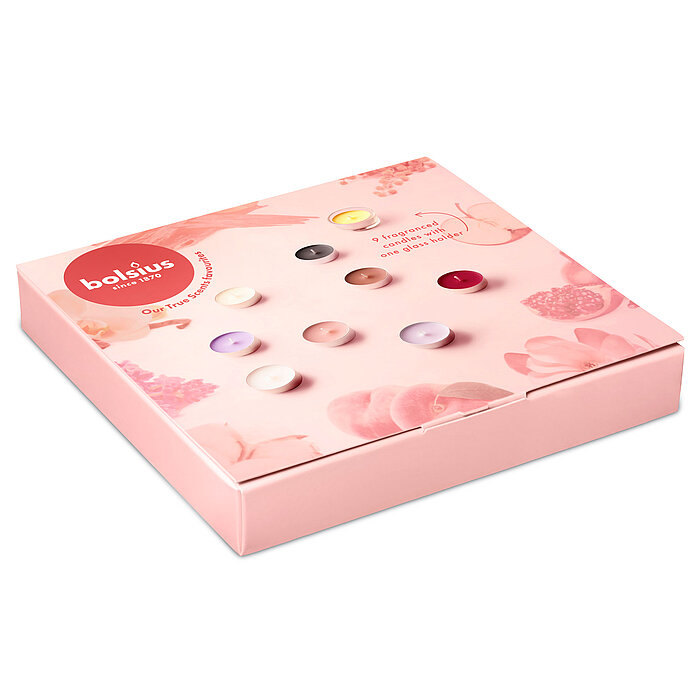 Eine rosafarbene Geschenkbox von Bolsius mit bunten Duft-Teelichtern und einem Teelichtglas.