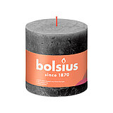 Eine durchgefärbte Rustik Stumpenkerze in der Farbe Stürmisches Grau mit den Maßen 100/100mm (H/DM). Der Banderole kann man die Marke "Bolsius" sowie die Hinweise "25% pflanzenbasiertes EU-Wachs", "0% tierisches Fett" und "Ohne Palmöl" ablesen.
