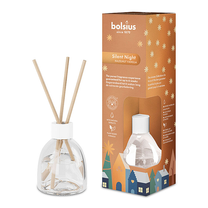 Ein Bolsius Raumduft-Diffuser mit Haselnuss-Vanille-Duft. Neben dem Diffuser steht die dekorative Verpackung des Artikels mit weihnachtlichem Motiv.